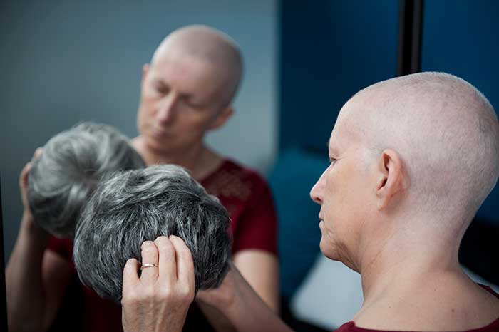 Woman with Cancer about to put on a wig